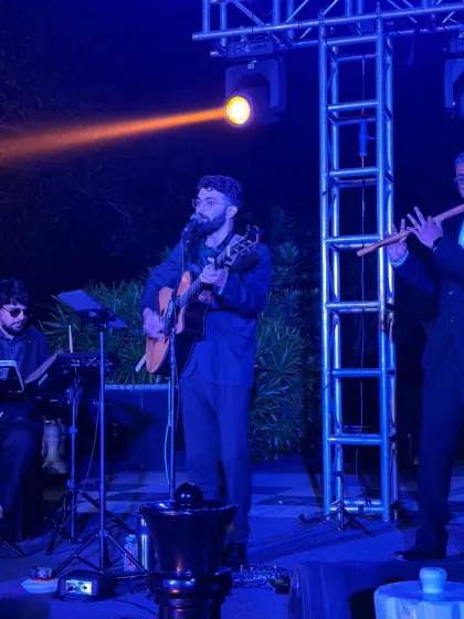 Blue stage lights catch our guitar and flute players mid-performance during the Golfshire corporate music set.