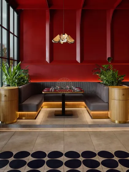 This U-shaped booth is perfect for larger groups, anchored by wooden planters that bring a touch of nature into the vibrant, red-walled space.