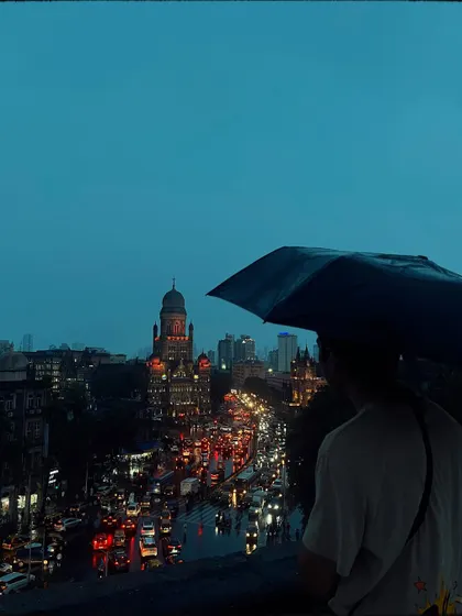 From a high vantage point, I captured this view of a man with an umbrella looking over the traffic-filled streets towards the iconic BMC building. It’s a portrait of a person and the city, showing a moment of pause above the chaos.