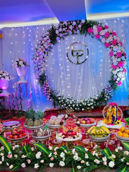 A stunning engagement or reception setup with a large floral ring backdrop and beautiful lighting. The stage is completed with a full display of my signature plate decorations.