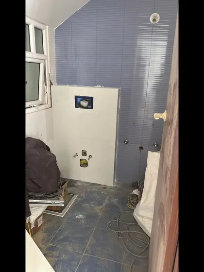 **BEFORE:** The powder room during construction, showing the initial plumbing and tile work before the final finishes were applied.