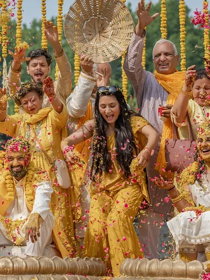 A shower of flower petals and a whole lot of laughter. This group photo captures the pure chaos and fun of a Haldi ceremony.