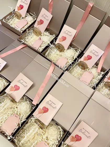 A top-down view of our bridesmaid proposal boxes being assembled. Each box includes a personal card and is carefully arranged with items like candles and luggage tags, creating a beautiful unboxing experience.