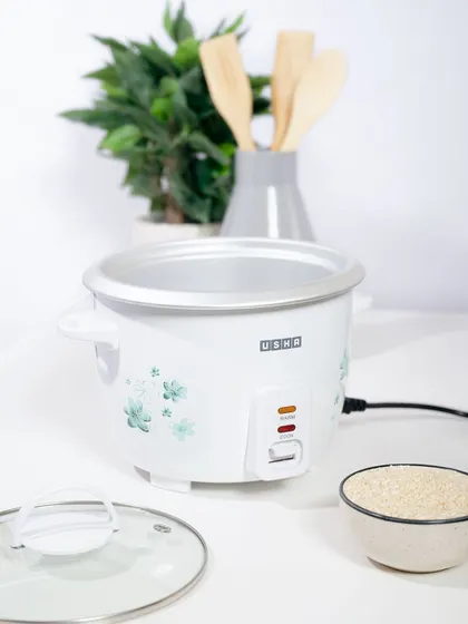 An "in-use" shot of the Usha rice cooker, showing it open with a bowl of rice nearby. This demonstrates the product's function and capacity in a simple, effective way.