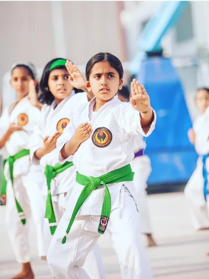 A student demonstrates a perfect shuto uke (knife-hand block), a key defensive move in Shotokan karate. Her focus is exemplary.