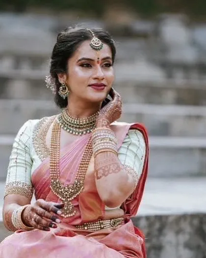 Pastels can be just as breathtaking for a wedding. This bride looks serene and beautiful in a soft pink Kanjeevaram saree, paired with a contrasting light green blouse with delicate embroidery.