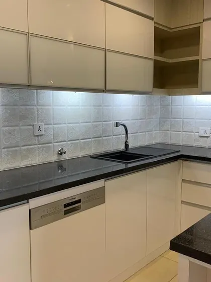This kitchen was designed for culinary masterpieces. A sleek, modern kitchen with glossy white cabinets, a black granite countertop, and integrated appliances.