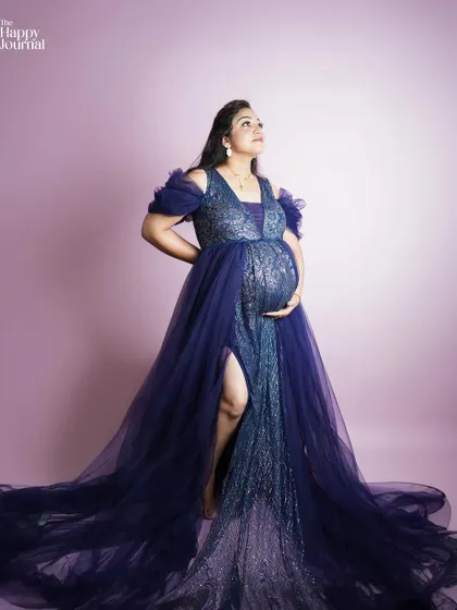 Looking up towards the light, this mother-to-be in a deep blue gown appears hopeful and radiant. The pose and lighting are designed to create a sense of wonder and anticipation.