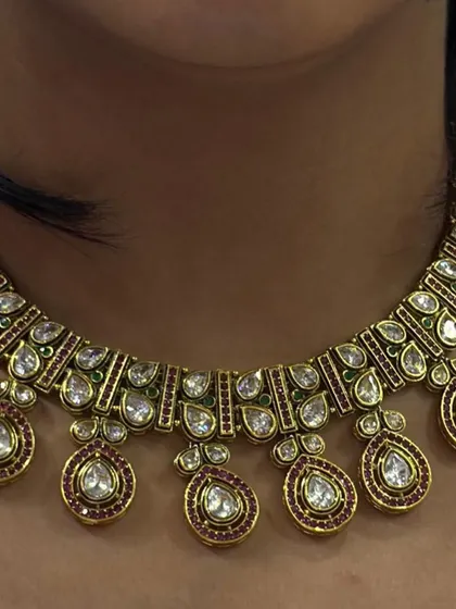 A close-up of a beautiful Polki necklace with ruby-coloured drops. The fine craftsmanship and antique finish give it a very rich and authentic look.