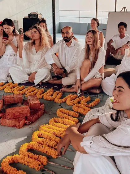 Students watch the opening ceremony with curiosity and reverence. The marigold garlands in the foreground are ready to be offered, symbolizing purity and new beginnings.
