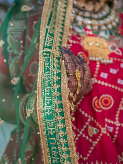 A detail shot of the bride's dupatta, embroidered with the auspicious Sanskrit blessing 'Sada Saubhagyavati Bhava'.
