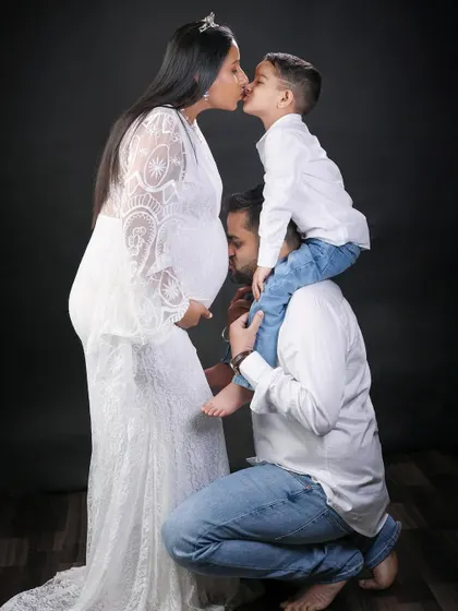 Kisses for mom and the baby. This pose captures the love from every angle, with the older son kissing his mom and the dad kissing the baby bump.
