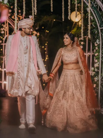 A romantic shot of the couple walking hand-in-hand through a beautifully lit archway on their wedding night.
