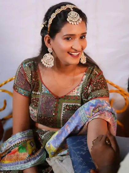 A candid moment from a Mehendi ceremony, with the bride's makeup looking soft and natural.