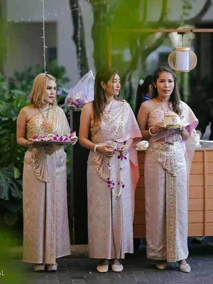 Hostesses in traditional Thai attire welcome guests with refreshing coconut water, adding a local touch to the destination wedding experience.