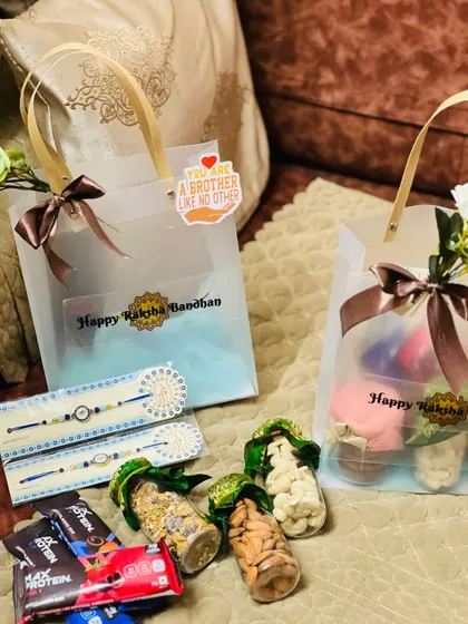 An assortment of Rakhi gifts, including gift bags, rakhi sets, and jars of nuts and snacks.