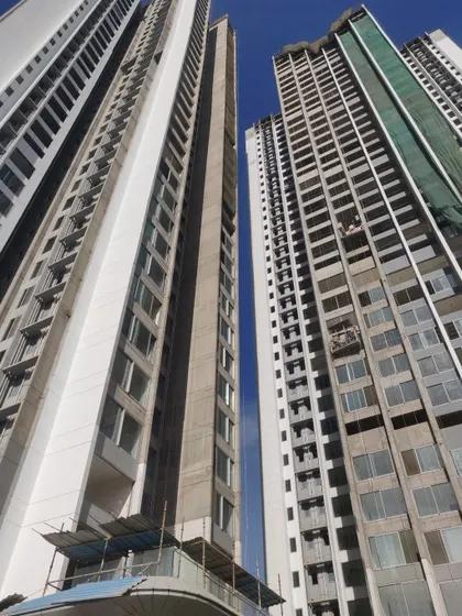 A low-angle shot of the Sunteck City towers under construction. This view highlights the scale of the project and the progress of the facade work, with large window openings designed for maximum natural light and ventilation.
