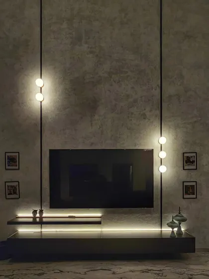 Details matter. Here, we used a combination of ambient and accent lighting to transform a simple TV unit into a dramatic focal point, highlighting the texture of the concrete wall and creating a moody, sophisticated atmosphere.