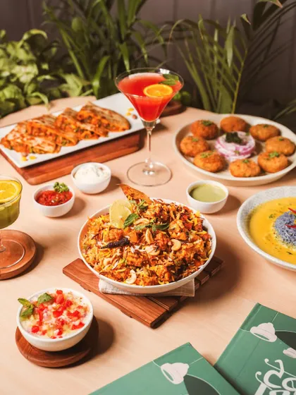 A vibrant table setting featuring a variety of modern Indian dishes. This shot is styled to feel like a real dining experience, complete with colorful cocktails, biryani, and appetizers.
