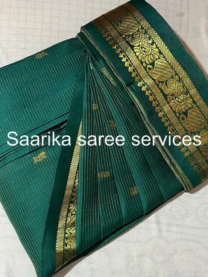 A deep green saree with a heavy gold border. The pleats are crisp and will hold their shape throughout the event.