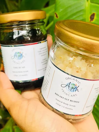 Meet my handmade body scrubs! On the left is 'Fine By Me', a coffee scrub, and on the right is 'Breakfast Buddy', a sugar scrub. Both are made with natural ingredients to exfoliate and nourish your skin.