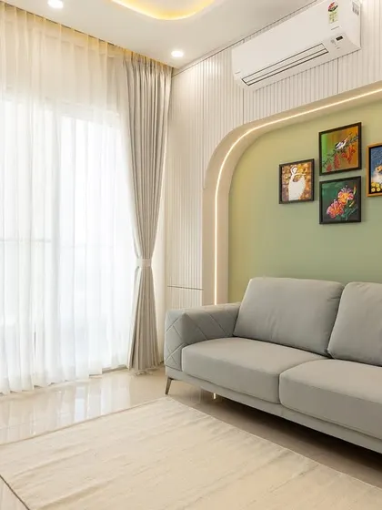 A quiet corner in a recreational room, featuring a comfortable sofa set against a soft green accent wall with an arched, backlit detail.