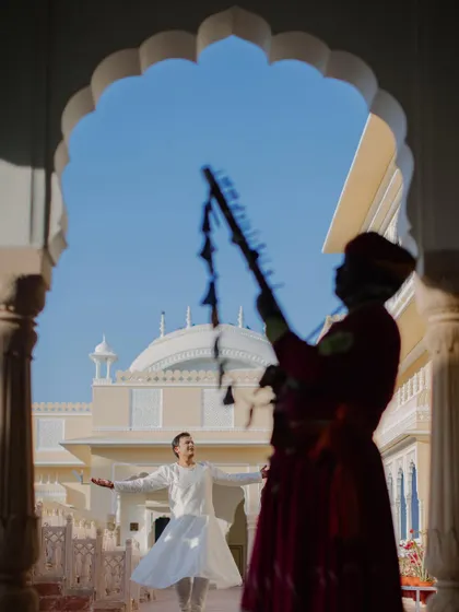 A fun, candid moment as the groom dances to the music of a traditional musician in the courtyard of a palace.