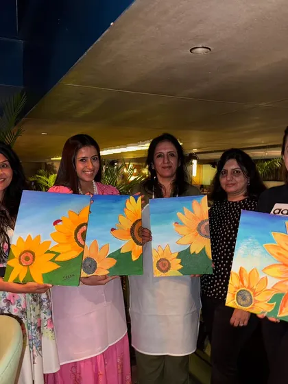 A group of friends proudly showing off their sunflower paintings after a fun and relaxed birthday party at Daysie All Day Cafe in Bangalore.