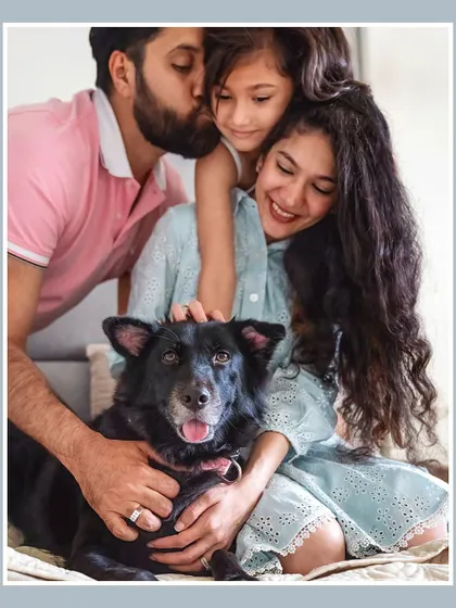 A beautiful family portrait with their daughter and their fluffy black indie dog, Pakodi.
