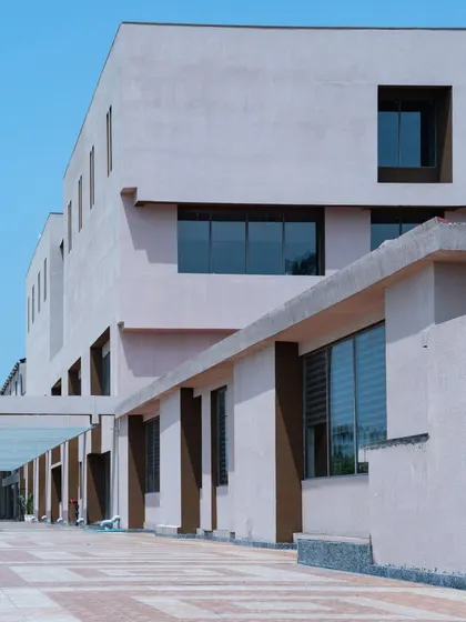 The patterned pavement of the walkway adds texture and visual interest to the exterior of Konark Academy. The design includes covered pathways that provide shelter and connect different parts of the building.