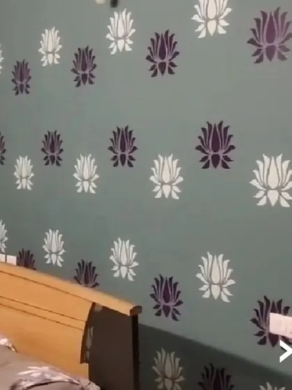 We specialize in creating unique decorative finishes. This bedroom accent wall features a delicate lotus stencil pattern in two tones over a muted green base, adding a personalized and artistic touch to the room without overwhelming the space.