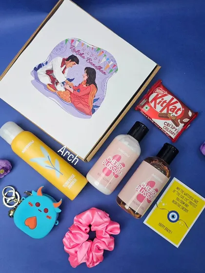 A cute and budget-friendly Rakhi hamper for your sister. This box includes a body spray, cherry blossom lotion, a quirky keychain, a scrunchie, and a KitKat, all with a custom illustrated lid.
