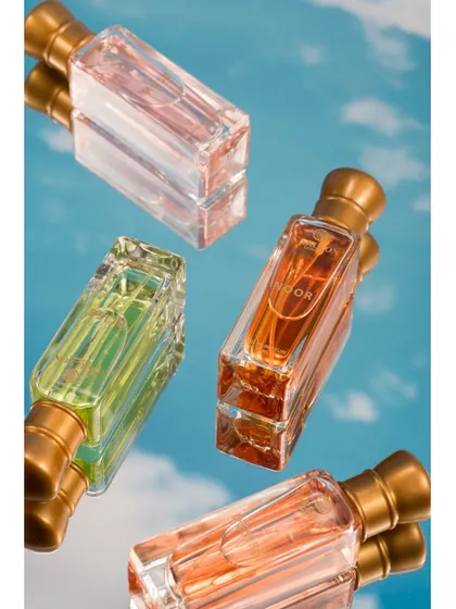 A clean, minimalist shot of perfume bottles reflected on a mirror against a sky backdrop. This top-down angle creates a unique and artistic perspective, focusing on the elegant shapes and colors of the bottles.