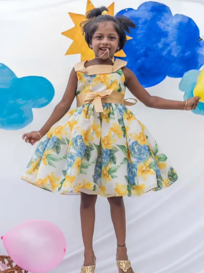Jumping for joy in a sunny yellow and blue floral dress. This dress is all about capturing the bright, happy moments of childhood.