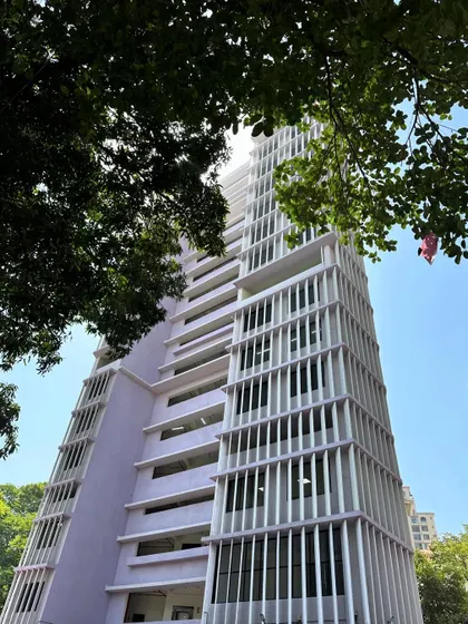Framed by trees, the facade of the Working Women's Housing showcases how climate-conscious design elements like shading fins can become the building's primary aesthetic feature.