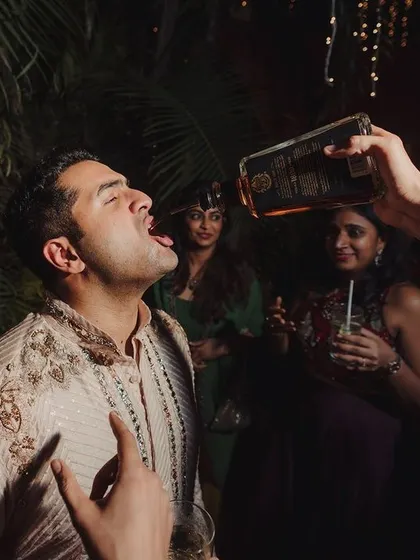 A groom enjoying a drink with his friends, a classic moment of celebration and camaraderie at a wedding party.