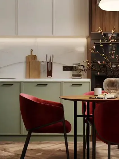 A cozy dining corner next to the kitchen, featuring sage green cabinets and plush red velvet chairs for a touch of elegance.