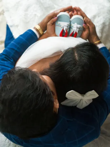 A creative top-down shot of the couple holding baby shoes. This angle provides a unique and artistic perspective for your announcement.
