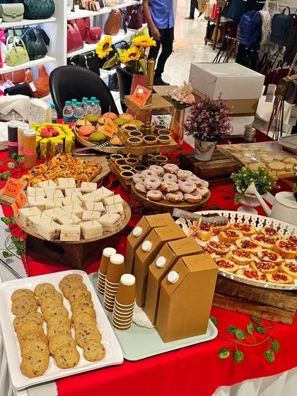 A wide shot of a grazing table we set up for a workshop at a Titan store. The spread includes cookies, sandwiches, donuts, tarts, and drinks for a complete hi-tea experience.