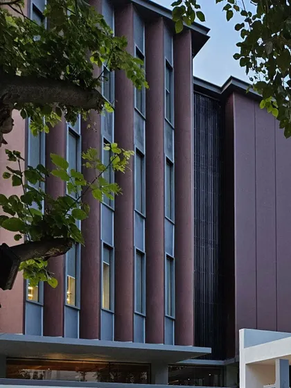 A detailed shot of the facade's vertical elements and fenestration. The rhythmic pattern of the windows and panels creates a dynamic and contemporary look, reflecting the modern workspace design within.