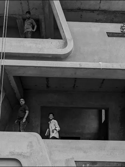 A candid moment on site, with team members observing the progress from the skeletal frame of a building's balconies.