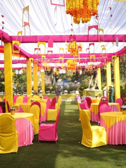 A full view of the Haldi seating area in Lonavala. We used bright yellow and pink chair covers and tablecloths under a tent of colorful drapes to create a completely immersive and festive environment.
