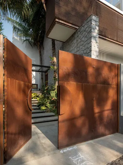 The floating steps of the entrance are designed to follow the natural slope of the land, flanked by existing coconut trees that were carefully preserved during construction.