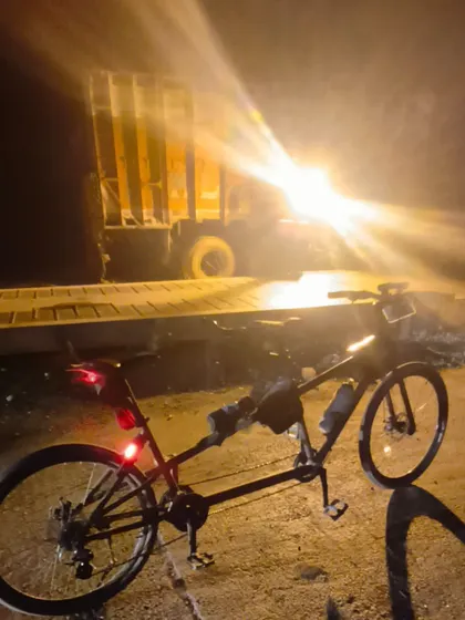 The tandem bike captured at night, with its lights cutting through the darkness of the highway.