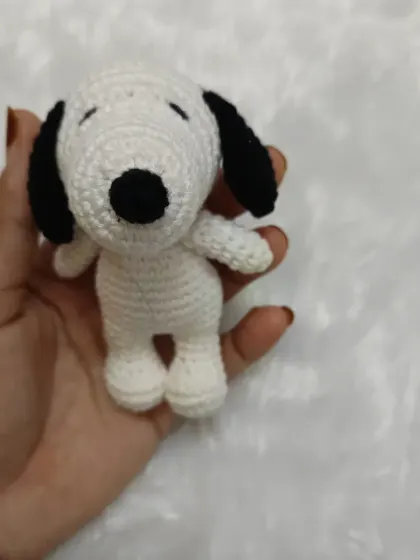 A front view of the handmade crochet Snoopy. He's small enough to be a keychain or bag charm, but still has all the classic details that make him so recognizable.