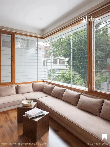 This cozy seating area in the Cube House is wrapped in large windows with wooden frames. The design maximizes natural light and provides a comfortable space to enjoy the views of the surrounding neighborhood.