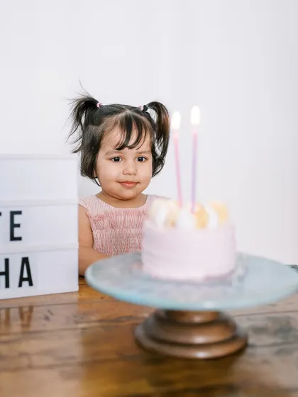 A little girl looking at her birthday cake. A simple, sweet moment from an at-home birthday celebration.