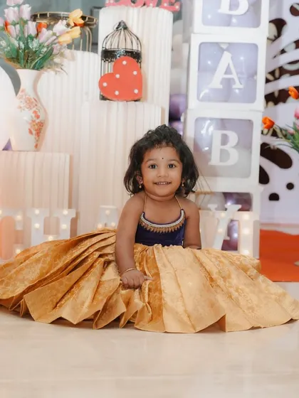 A joyful shot showcasing the full volume and beautiful drape of the golden silk brocade lehenga. The design ensures that the child is comfortable and can move freely, making it perfect for long events and festive fun.