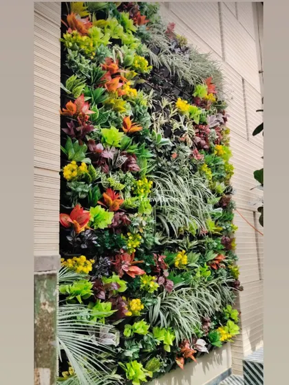 A custom vertical garden featuring a mix of green, red, and yellow artificial plants, adding a burst of color to an exterior wall.