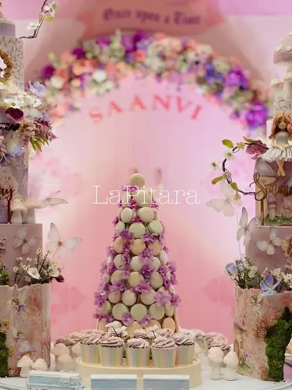 The magnificent dessert table, featuring two elaborate cakes, a macaron tower, and other sweet treats, all designed to match the enchanted forest theme.